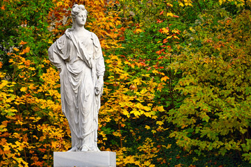 Old stone statue and colorful autumn foliage in park, Vienna, Austria