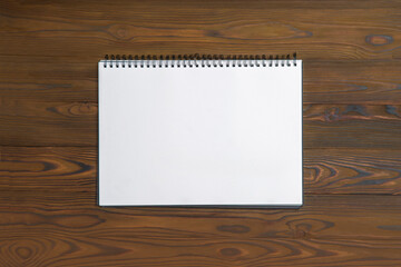 Album notebook with white sheets for painting on a wooden table. Copy space, empty blank, mock up
