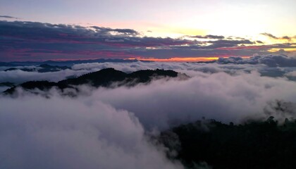 Fototapeta premium A dramatic sunrise view over a landscape of mountains shrouded in clouds.