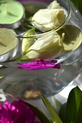 Close-up of a glass vase filled with water, with white flowers and waterfowl candles