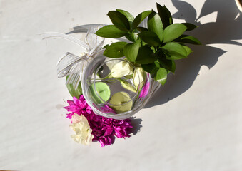 green waterfowl candles and white flowers in the water in a transparent round vase top view