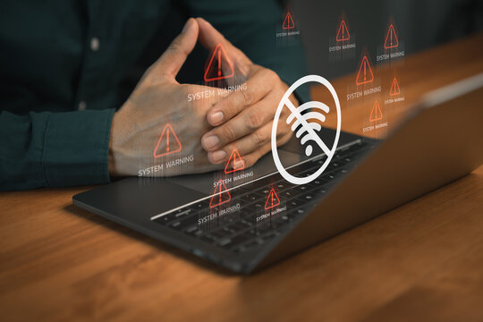Person using laptop computer with warning icon and a no Wi-Fi signal symbol. Idea for IT security service and digital risk content, digital error, internet connection failure, malware, data breaches.