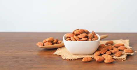 Almonds in white bowl on wooden table background
