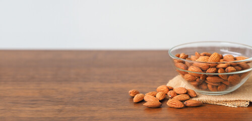 Almonds in glass bowl on wooden table background