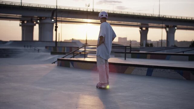 Man skater in helmet stands alone on modern skating ramp
