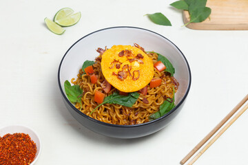 A simple yet satisfying meal of Indomie Goreng with a fried egg. The image emphasizes the rich...