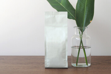 White blank coffee bag on wooden table. Packaging mockup with empty space for you designs.