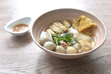 boiled dory fish and fishball with bean sprout topping crispy dumpling in soup on bowl dipping...
