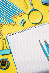 Flat lay of school stationery including notebook, pens and clips on yellow background. Great for...