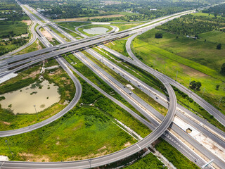 Drone shot a large highway interchange crossing over green farmlands in Thailand
