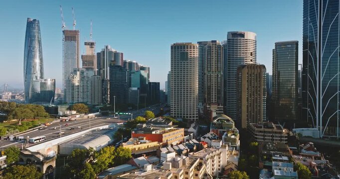 Australia, Sydney: Aerial view of Sydney city skyline with towering skyscrapers, construction cranes, traffic road highway and low rise buildings at sunrise. Modern architecture. Drone flight footage