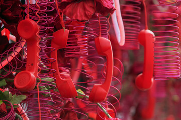 Vibrant red telephone handsets with coiled cords intertwined with deep pink flowers