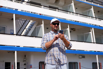 Tourist using smartphone near cruise ship on sunny day