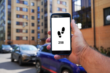 Man holding smartphone showing pedometer app in residential area