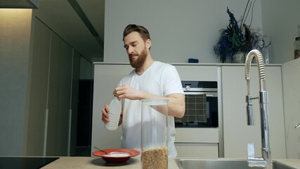 Male yoga mentor pours into a plate from a bottle and closes the lid and puts it in the refrigerator and then stirs with a spoon