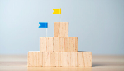 Pyramid of wooden blocks with miniature flags on top. Achievement, goal setting and strategy