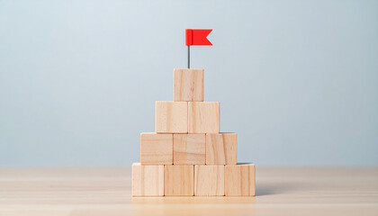 Pyramid of wooden blocks with miniature flags on top. Achievement, goal setting and strategy