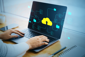 Cloud data upload concept on laptop screen with folders and documents, person working at wooden...