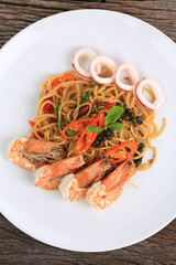 Stir Fried Spicy spaghetti with mixed seafood and herb on white plate, Thailand food style