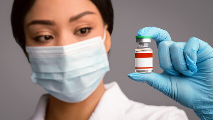 Black doctor woman holding tube with Covid-19 Coronavirus vaccine, ready for vaccination against...