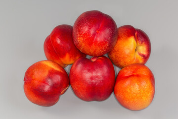 Several ripe nectarines on a gray background