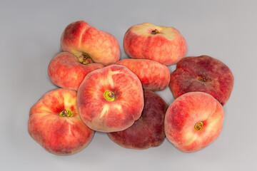 Heap of ripe flat peaches on a gray background