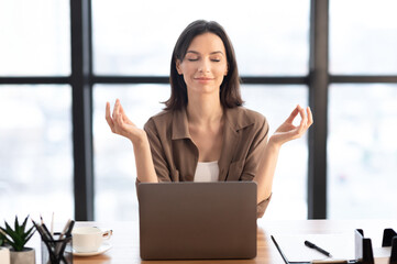 Mental Hygiene. Calm beautiful girl meditating at workplace, dealing with stress and anxiety. Empty space