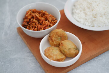 Indonesian Cuisine Tempe, perkedel, and Rice on a Wooden Board