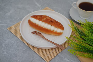Cream-Filled Almond Bun on White Plate with Tea