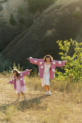 Fototapeta premium A young mother and daughter are walking in nature among the mountains in beautiful identical sweaters