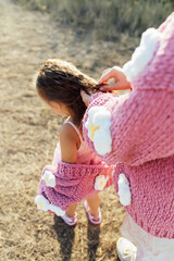 Obraz premium A young mother and daughter are walking in nature among the mountains in beautiful identical sweaters