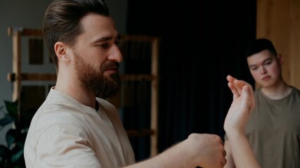 A male yoga mentor and a female student show an exercise while he talks