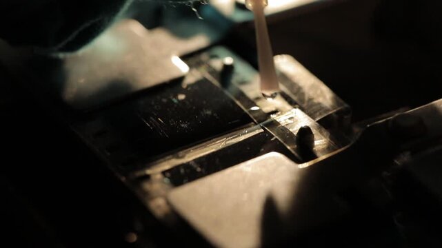 This video captures the intricate process of splicing film with a gloved hand. A close-up view reveals a metal splicing machine, with a roll of film being carefully maneuvered and joined.