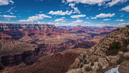 Dramatic sky over a canyon with vivid red rocks and snow-capped peaks