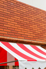 Striped red awning with red brick wall of cafe,Red White Tents, market umbrella,Front tent roof for...