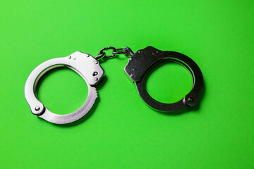 Silver handcuffs on green background