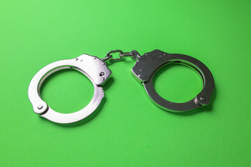 Silver handcuffs on green background