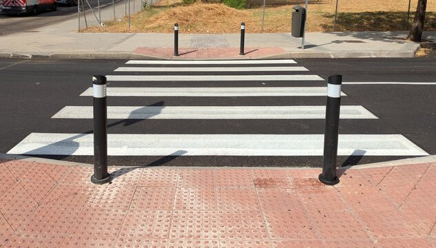 Paso de peatones con postes de se&ntilde;alizaci&oacute;n y acera con superficie antideslizante y retumbante