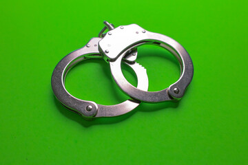 Silver handcuffs on green background