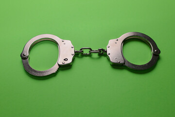 Silver handcuffs on green background
