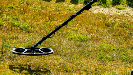 a man walks through a field with a metal detector