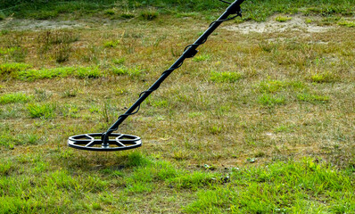 a man walks through a field with a metal detector