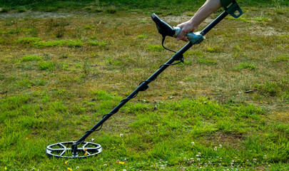 a man walks through a field with a metal detector