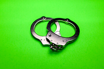 Silver handcuffs on green background