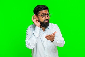 Indian man frowns, places hand to ear as if struggling to hear, expressing confusion and surprise...