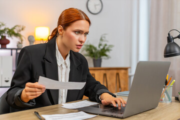 Young businesswoman at home office finds unpaid bill on laptop jaw drops begins fast urgent...