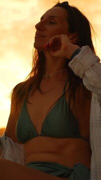 Woman, sunset, nature relaxing at golden hour in a bikini. Vertical video.