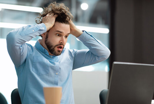 Oh No, Error Concept. Portrait of shocked scared man sitting at desk using pc, gasping with open mouth and grabbing his head. Stressed worried man suffering business problems reading bad negative news