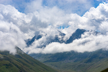 Clouds enveloping mountain peaks in a green valley