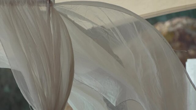 Fabric, flowing, translucent white curtain blowing gently, revealing faint silhouette, serene atmosphere.